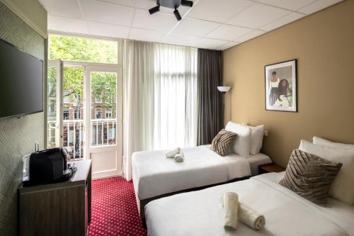 a hotel room with two beds and a television at Hotel Atlantis Amsterdam in Amsterdam