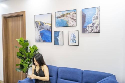 une femme assise sur un canapé bleu dans un salon dans l'établissement Hoàng Anh Hotel, à Nha Trang