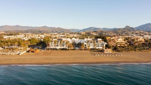 METT Hotel & Beach Resort Marbella Estepona في إِستيبونا: اطلالة على شاطئ به بيوت وماء