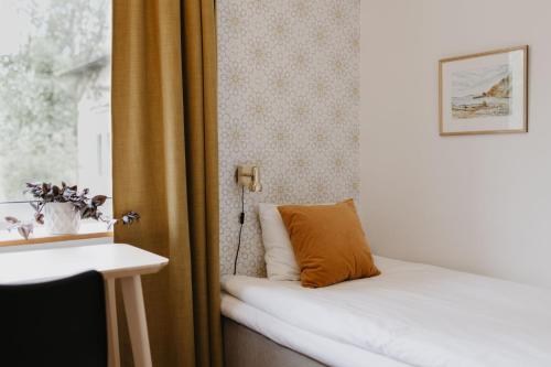 a bed in a room with a window and a pillow at Vassbo Vandrarhem in Falun