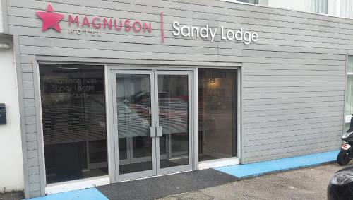 a store with two glass doors and a sign on it at Magnuson Hotel Sandy Lodge Newquay in Newquay