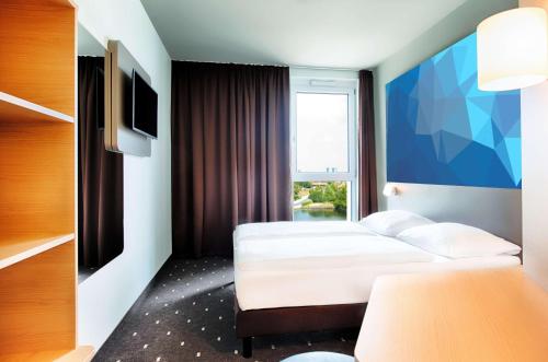 a hotel room with two beds and a window at B&B HOTEL Offenburg-Hbf in Offenburg