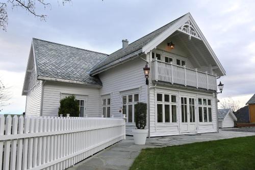 une maison blanche avec une clôture blanche dans l'établissement Alnes Gård, à Ålesund