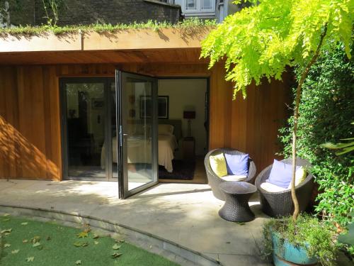 a patio with two chairs and a sliding glass door at Romantic Bungalow in Notting Hill in London