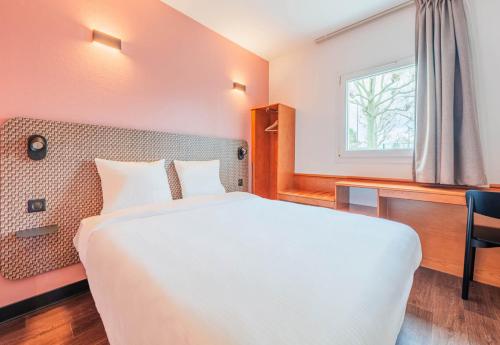 - une chambre avec un grand lit blanc et une fenêtre dans l'établissement B&B HOTEL Strasbourg Nord Mundolsheim, à Mundolsheim