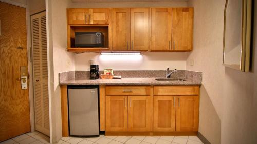 a kitchen with wooden cabinets and a sink and a microwave at Aston at the Executive Centre Hotel in Honolulu