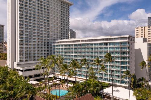 an office building with a pool and palm trees at Sheraton Princess Kaiulani in Honolulu