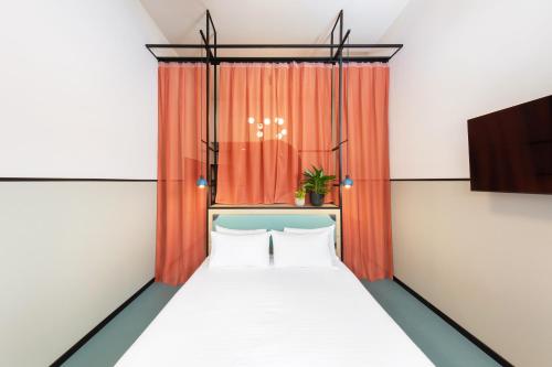 a bed in a room with an orange curtain at CX Milan Bicocca in Milan