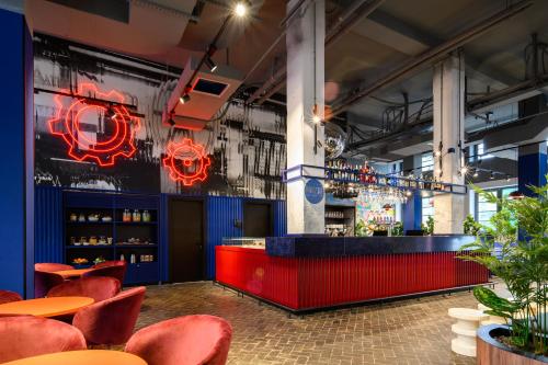 a bar with red chairs and a red counter at CX Milan Bicocca in Milan