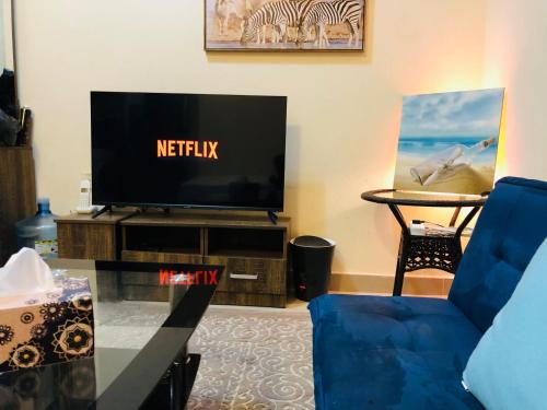 - un salon avec une télévision et un canapé bleu dans l'établissement Premium Furnished studio, à Charjah