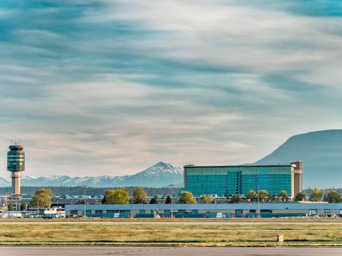 a building with a water tower and mountains in the background at Fairmont Vancouver Airport In-Terminal Hotel in Richmond