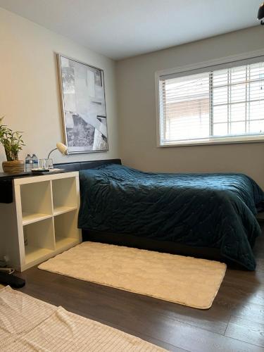 a bedroom with a bed with a black comforter and a window at Vancouver Airport Cozy room 舒适小屋, Richmond,near YVR in Richmond