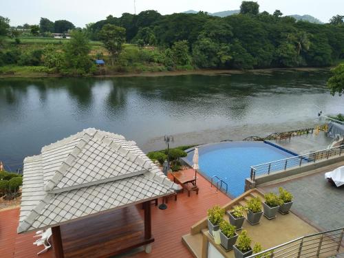 a swimming pool on a deck next to a river at Princess River Kwai Hotel in Kanchanaburi City