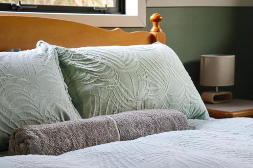 a bed with white pillows and a wooden head board at Kanuka Ridge Lodge in Marahau