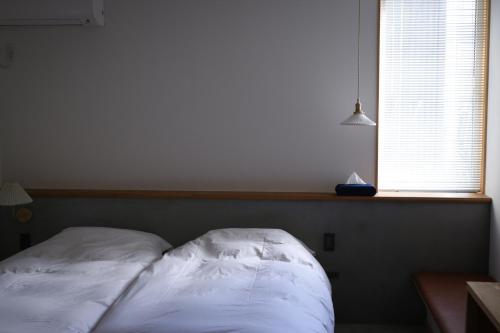 un letto bianco in una stanza con finestra di Lemonsea Onomichi a Onomichi