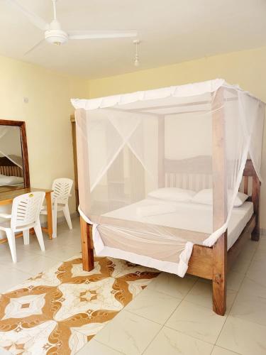 - une chambre avec un lit à baldaquin, une table et des chaises dans l'établissement Casuarina Lounge, à Malindi