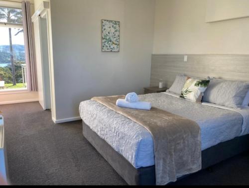 a bedroom with a bed with a towel on it at Norfolk Pines Motel in Merimbula