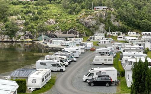 un gruppo di veicoli parcheggiati in un parcheggio vicino a un fiume di Kyrping Camping a Kyrping