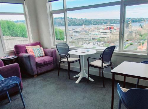 a waiting room with chairs and tables and windows at Travel Stay City Hostel in Dunedin