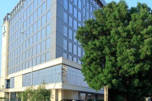 ein hohes Gebäude mit einem Baum davor in der Unterkunft Clarion Hotel Jeddah Airport in Dschidda