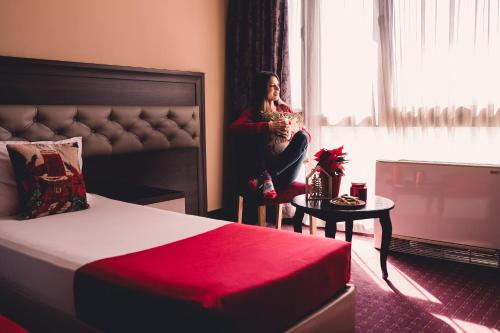 a woman sitting on a bed in a hotel room at Business Hotel Plovdiv in Plovdiv