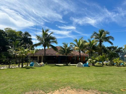 a house with palm trees in front of a yard at Acquamarine Park Hotel in Guarapari