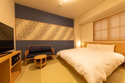 1 dormitorio con 1 cama, TV y silla en Onyado Nono Asakusa Natural Hot Spring, en Tokio