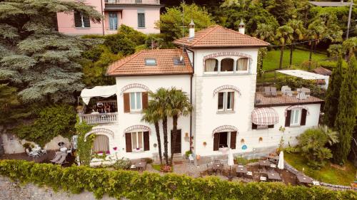 a white house with a palm tree in front of it at Villa Varenna in Varenna