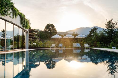 - une piscine avec des chaises et des parasols à côté d'un bâtiment dans l'établissement A-ROSA Gardasee, à Salò