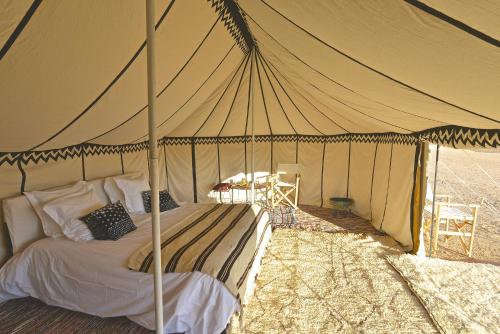 ein Schlafzimmer mit einem Bett in einem Zelt in der Unterkunft Dar Inacamp in El Mjed