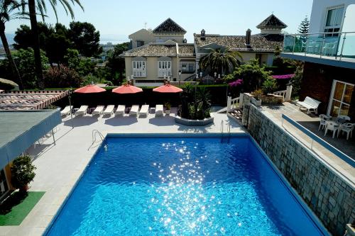 a swimming pool in front of a house at Hotel Complejo Los Rosales in Torremolinos