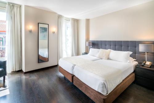 a bedroom with a large bed and a large window at Rossio Garden Hotel in Lisbon