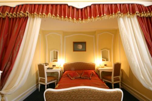 a bedroom with a bed with red curtains and two tables at Hotel Leopold I in Novi Sad