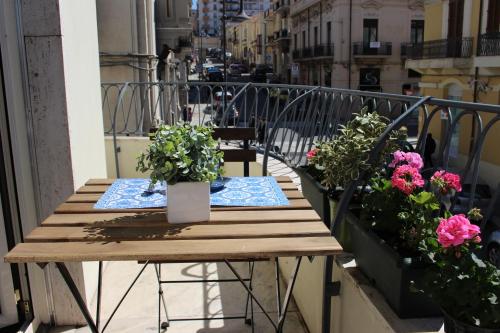 a wooden table on a balcony with flowers at La Casa di Aurora in Reggio di Calabria