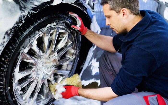 man washing car wheel with sponge soap