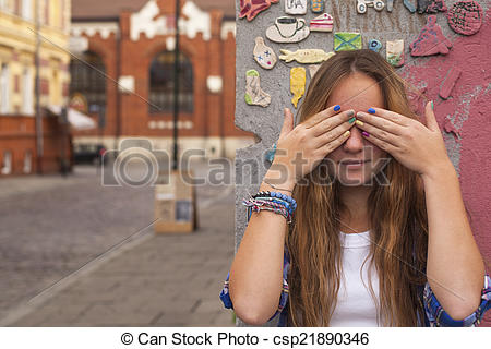 Stock Photo of Pretty young girl closing eyes with hands on the.