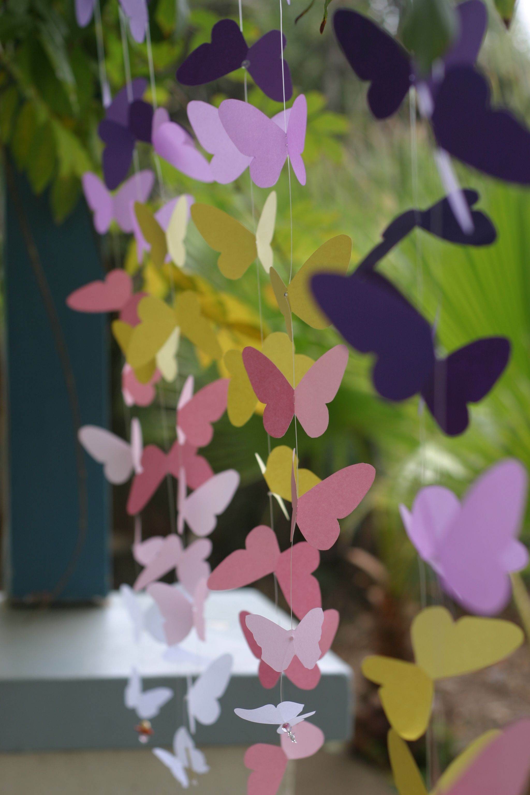 Paper butterflies threaded onto fishing line and suspended.