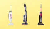 Three upright vacuum cleaners from Sebo, Shark and Vax lined up on a yellow background