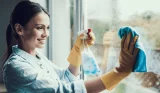 Smiling woman cleaning window