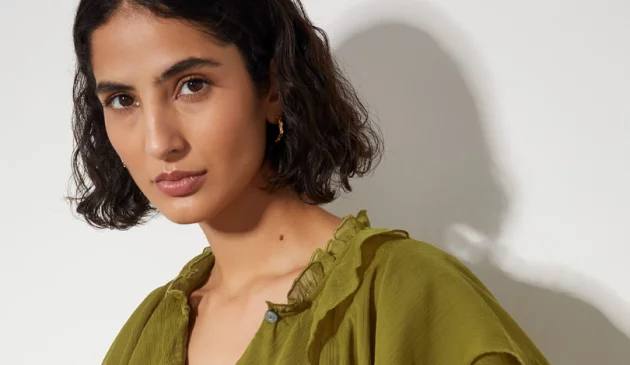 A model from Monsoon is looking at the camera in a green blouse