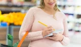 woman writing shopping list at supermarket