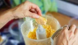 Hand adding food to a food processor