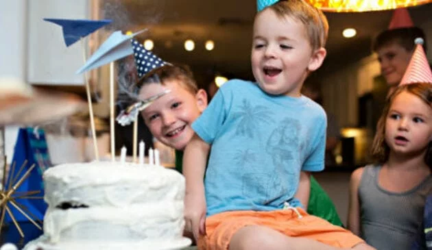 child sat next to birthday cake