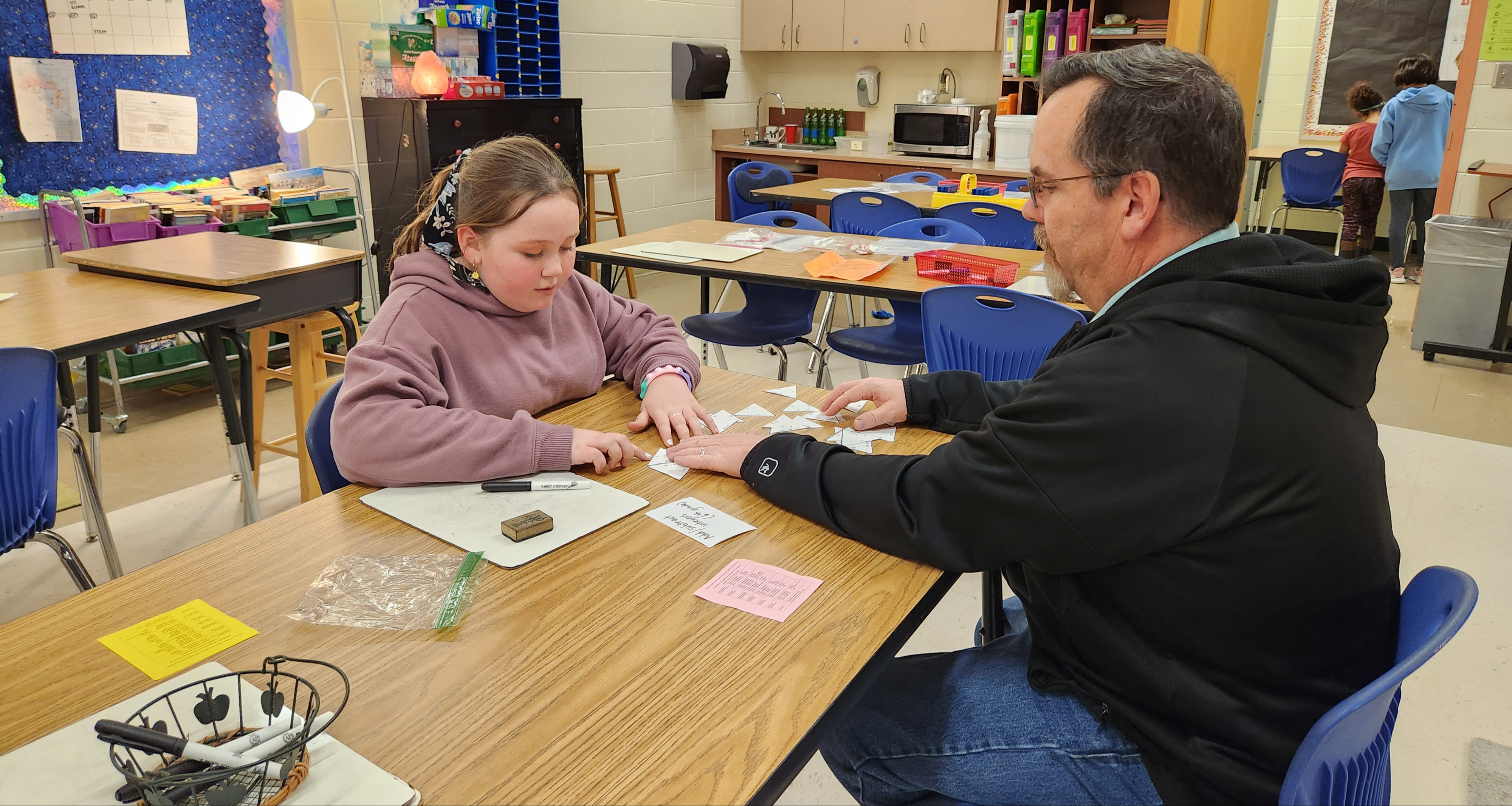 A father helping out her daughter in class