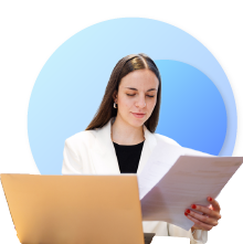 a woman working, looking at papers and a laptop