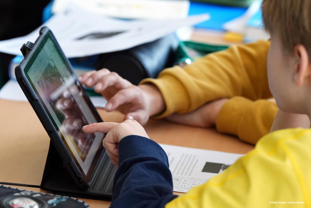 A teacher and student using a tablet together in a classroom.