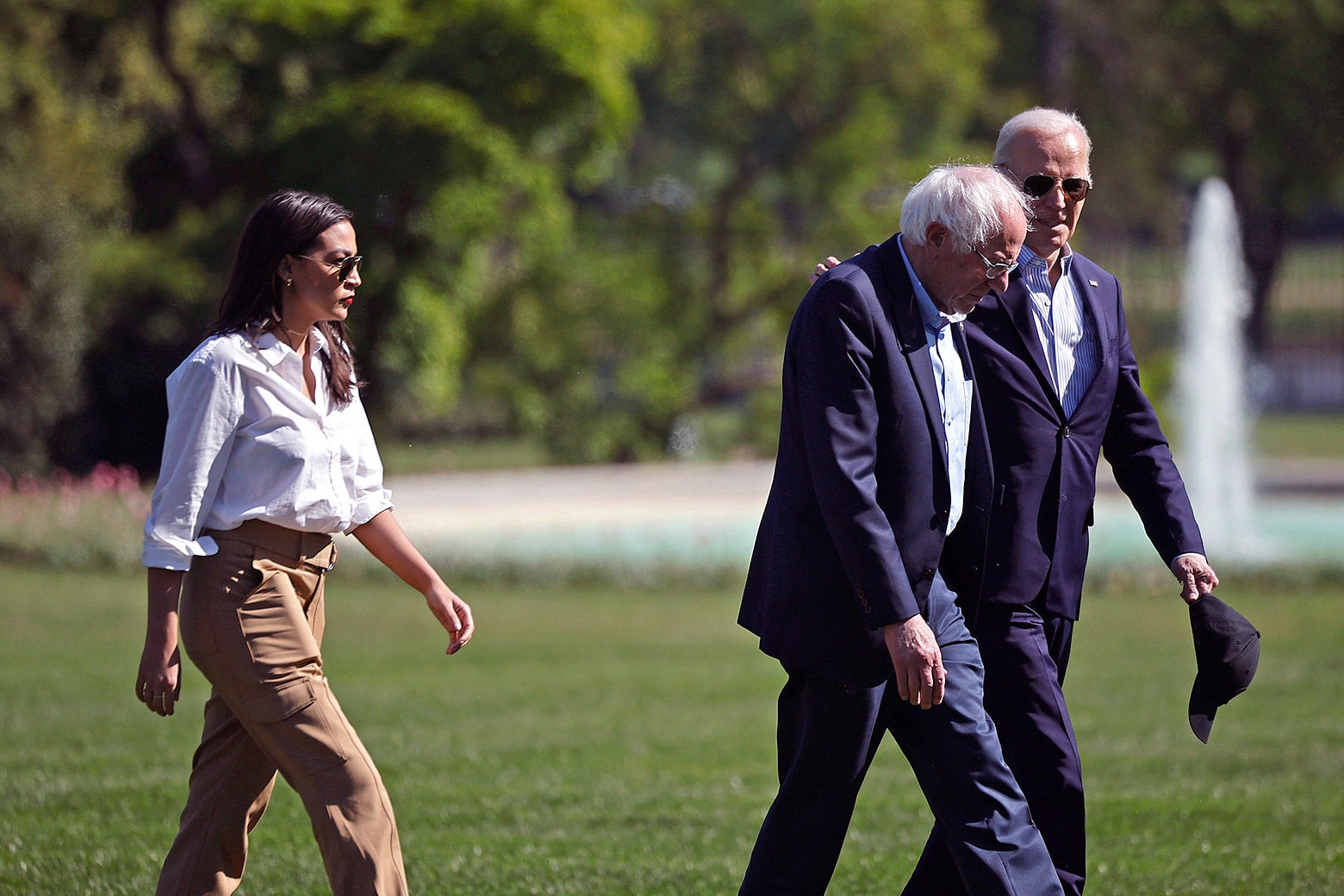 Two men walk together. A woman is close behind them.