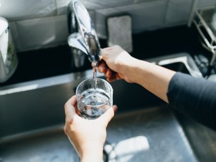 Cropped shot of woman's hand filling a glass of filtered water right from the tap in the kitchen sink at home