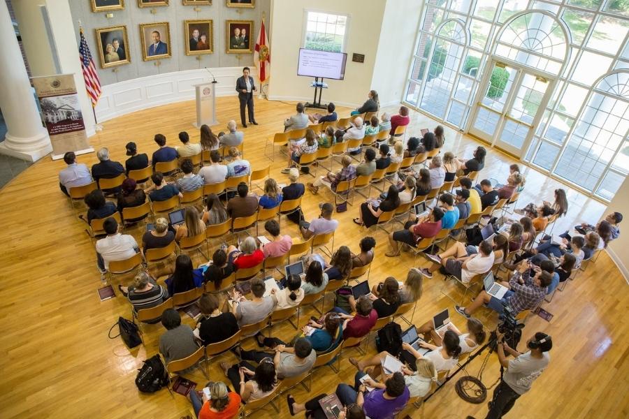 Students sitting in a large auditorium/ lecture hall