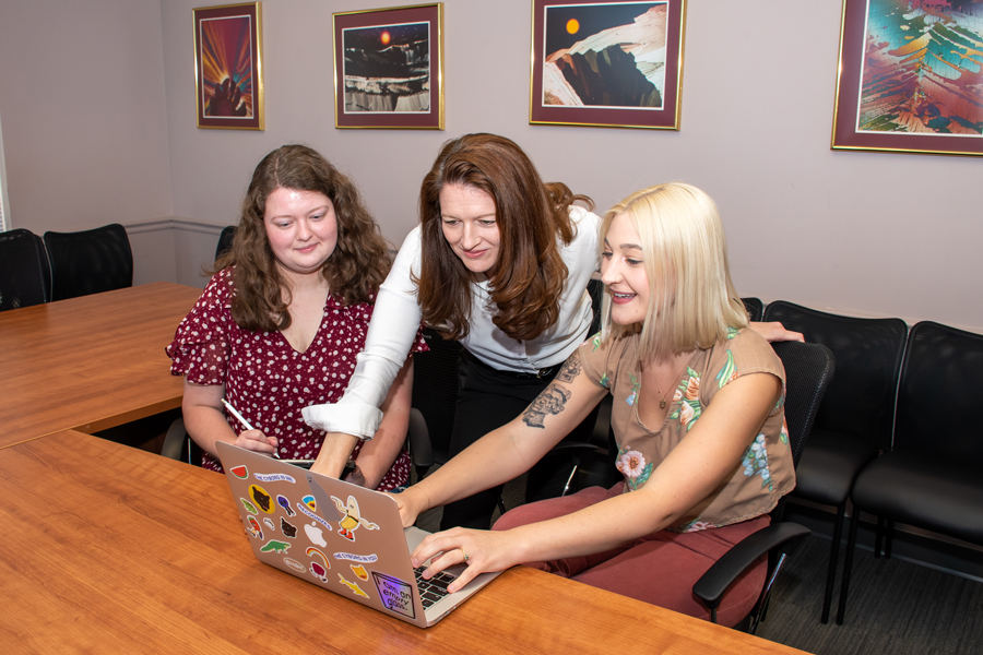 FSU Sociology professor Dawn Carr working on a laptop with Sociology students and staff